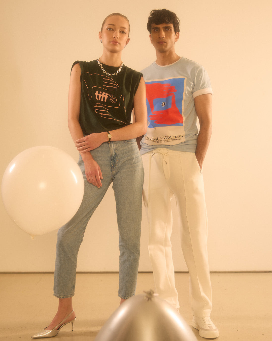 Two people standing side by side with a large balloon and metallic balloon t in the foreground.