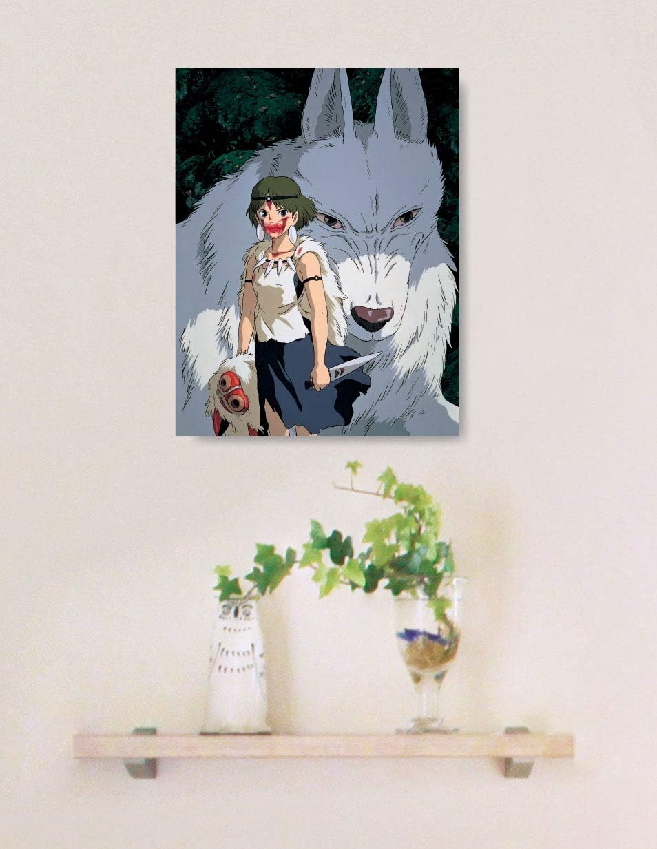 A framed art print puzzle of Princess Mononoke standing with Moro the wolf god hangs on a wall above a small wooden floating shelf.


