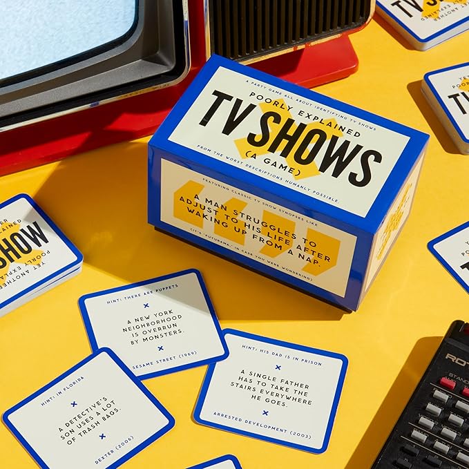 A box for the party game "TV Shows Poorly Explained" sits on a yellow surface surrounded by game cards featuring humorous, oversimplified synopses of popular television series.