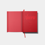 An open, vibrant red hardcover book titled "Anora" in a stylized cursive font, featuring a matching red ribbon bookmark and a minimalist design.