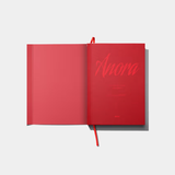 An open, vibrant red hardcover book titled "Anora" in a stylized cursive font, featuring a matching red ribbon bookmark and a minimalist design.