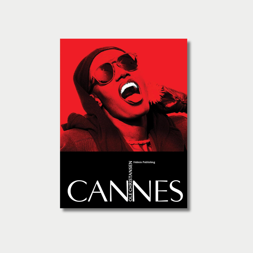 Book cover titled "CANNES" by Ole Christiansen, featuring a striking high-contrast photograph of Grace Jones wearing sunglasses and joyfully sticking her tongue out against a vibrant red background.