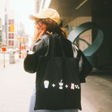 Person wearing a black tote bag with icons on a city street
