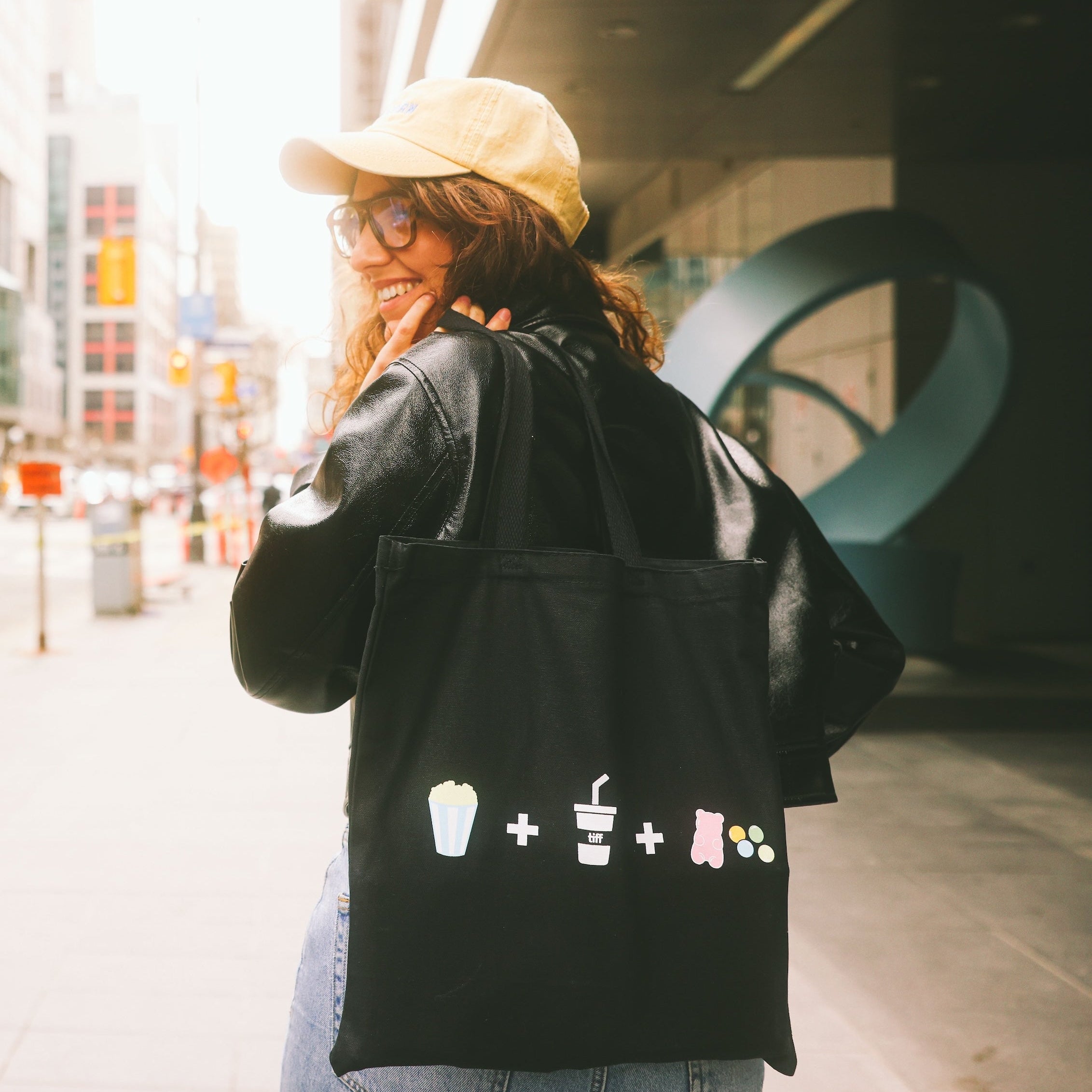Person wearing a black tote bag with icons on a city street