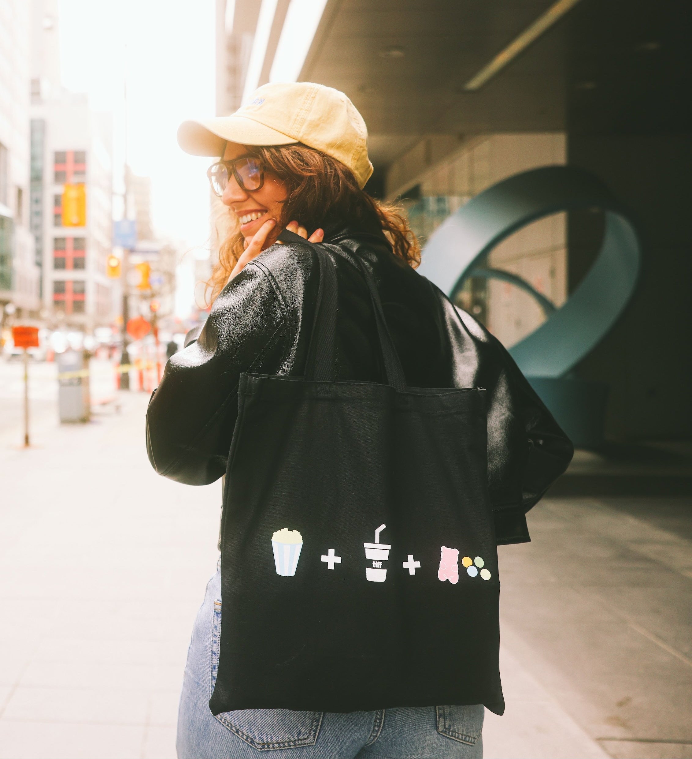 Person wearing a black tote bag with icons on a city street