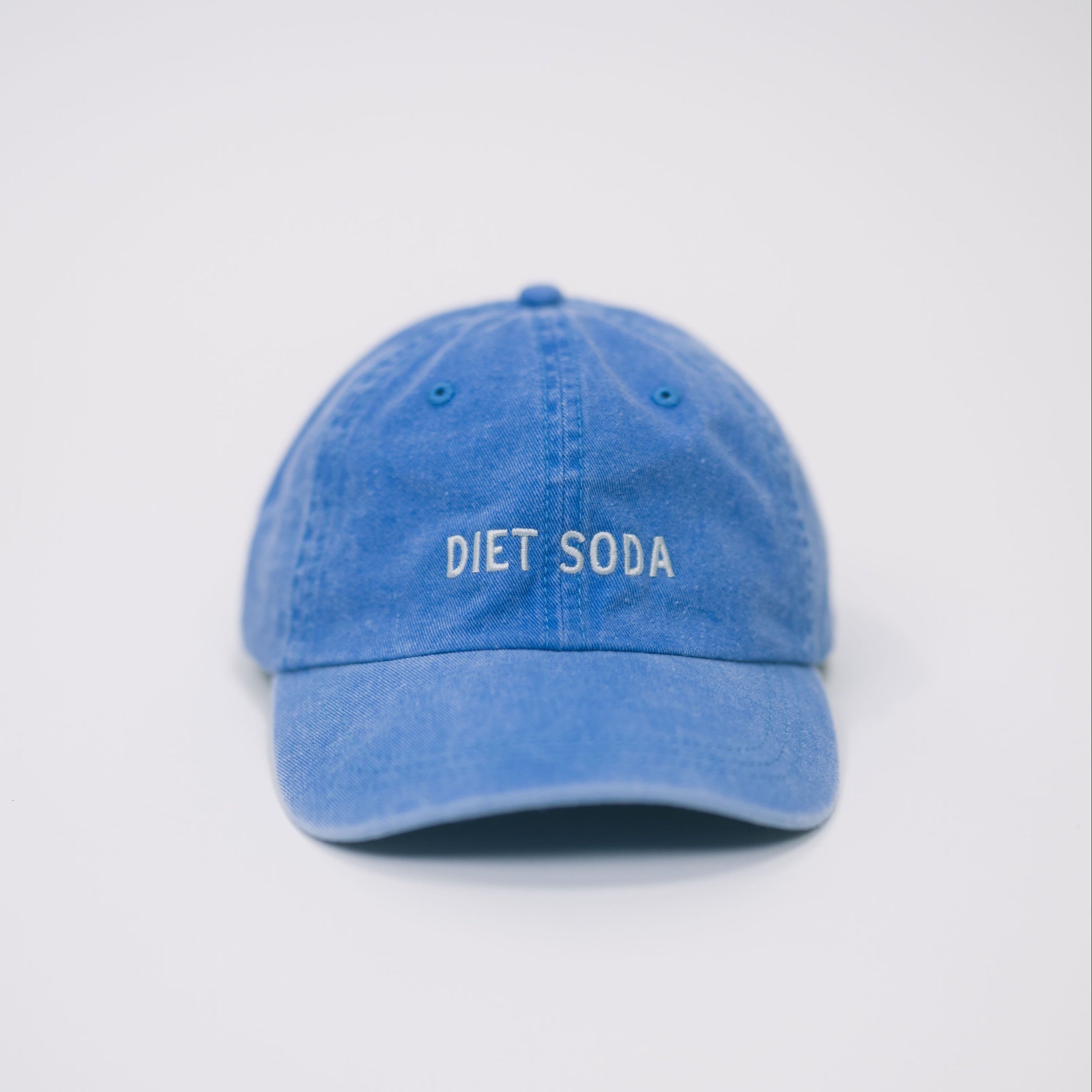 Front view of a blue baseball cap on a white background, featuring “Diet Soda” embroidered in white on the front.