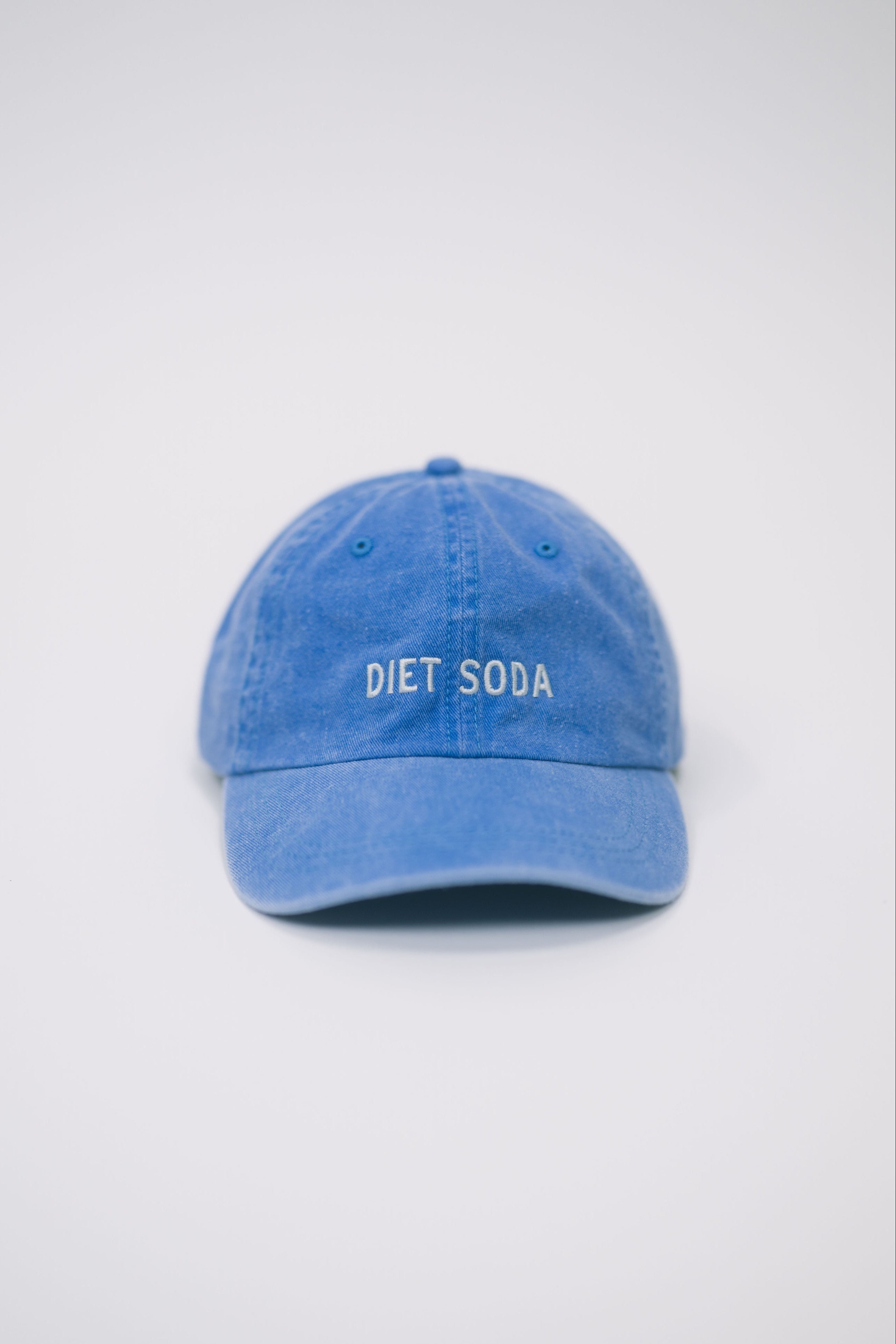 Front view of a blue baseball cap on a white background, featuring “Diet Soda” embroidered in white on the front.