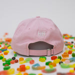 Back view of pink baseball cap on a white background with assorted candies, featuring “TIFF” embroidered in white.