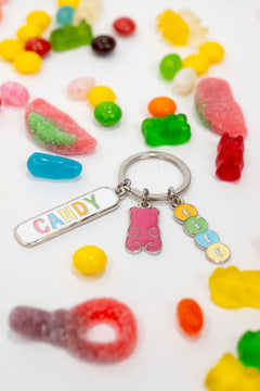 Assorted candy gummies on a white background alongside a silver-tone keychain with three charms: a gummy bear, a “TIFF” tag, and a “Candy” tag.