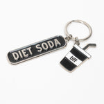 Silver-tone keychain on a white background featuring two charms: a black “Diet Soda” tag and a soda cup with a straw.