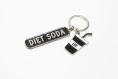 Silver-tone keychain on a white background featuring two charms: a black “Diet Soda” tag and a soda cup with a straw.