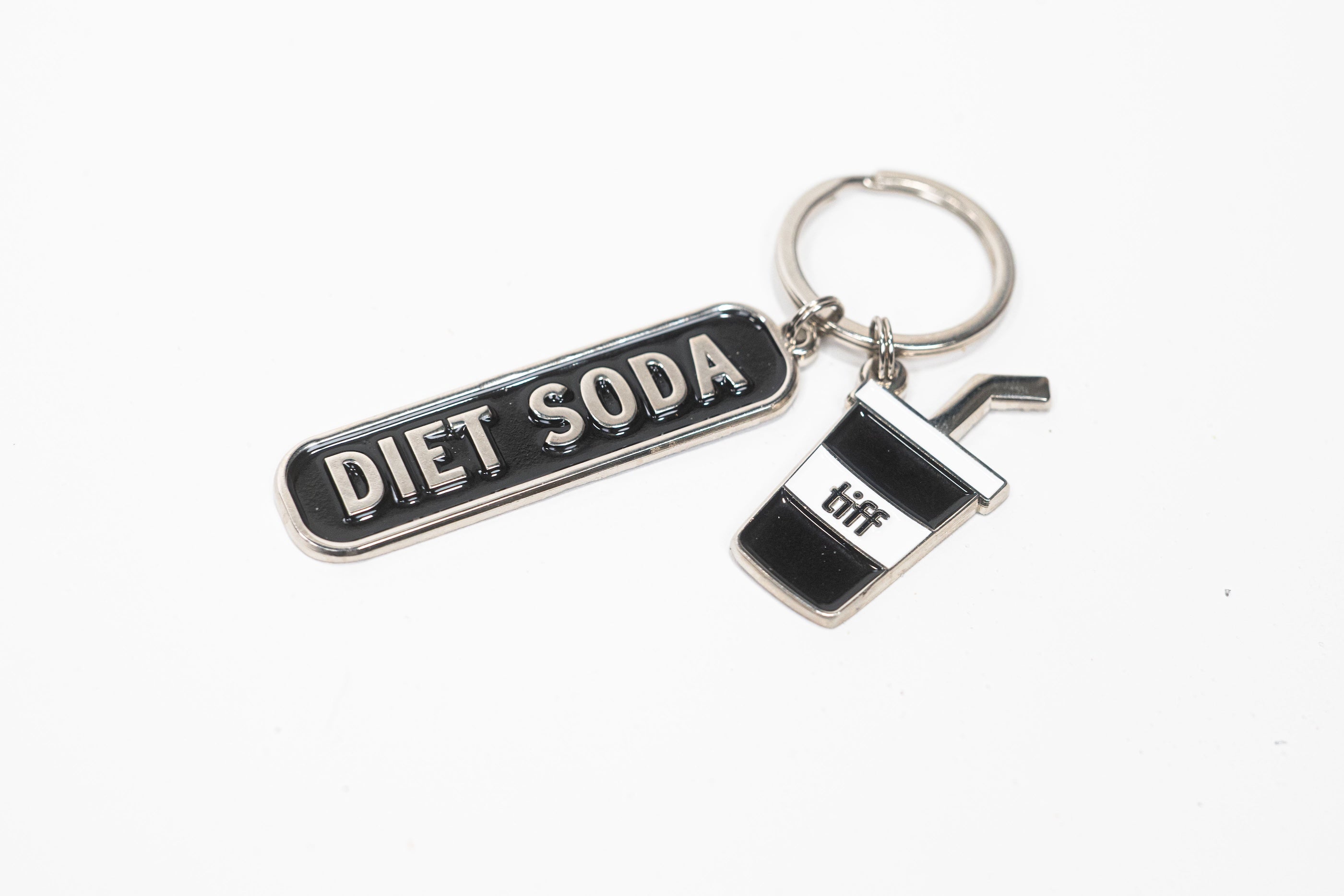 Silver-tone keychain on a white background featuring two charms: a black “Diet Soda” tag and a soda cup with a straw.