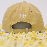 Back view of yellow baseball cap on a white background with popcorn surrounding it, featuring “TIFF” embroidery in white. 