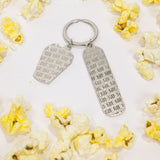 Silver-tone keychain on a white background featuring back of two "TIFF" embossed charms surrounded by yellow popcorn.