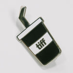 Black and white soda cup shaped enamel pin with the TIFF logo at center on a white background.