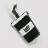 Black and white soda cup shaped enamel pin with the TIFF logo at center on a white background.