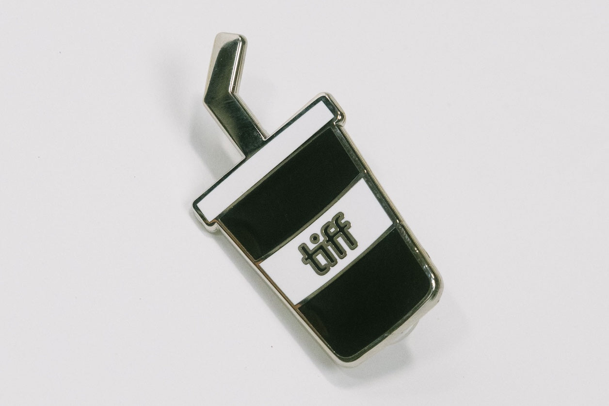 Black and white soda cup shaped enamel pin with the TIFF logo at center on a white background.