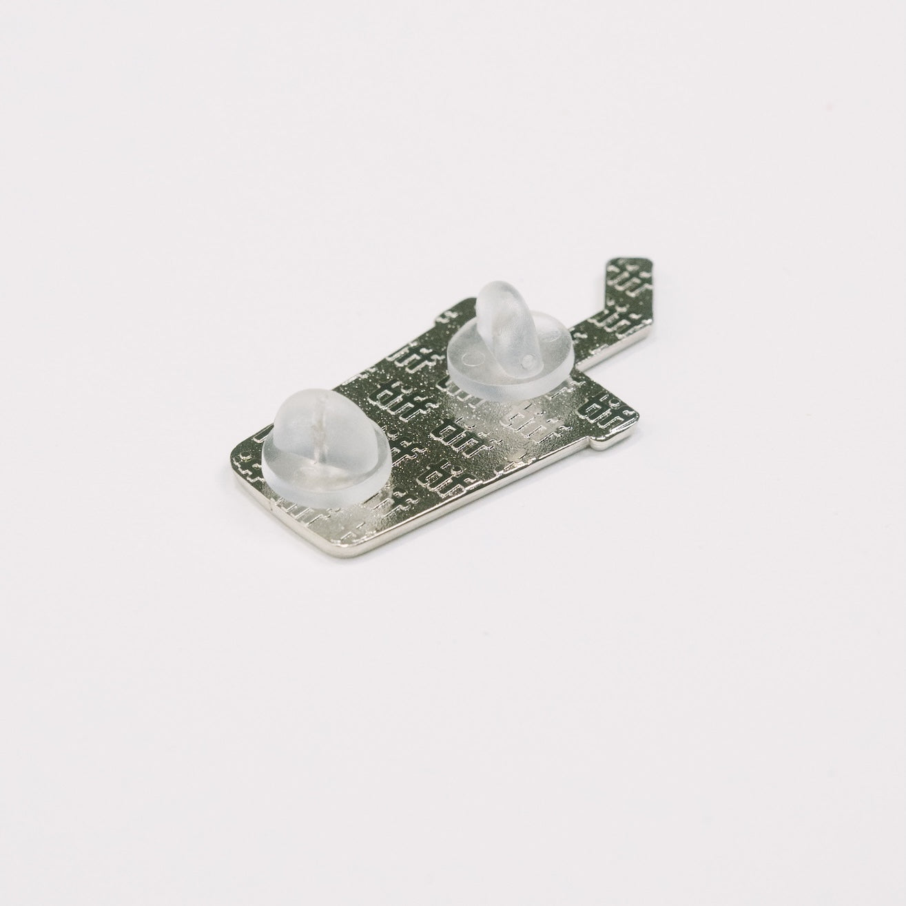 Back view of a soda cup shaped enamel pin in silver on white background, featuring an embossed TIFF monogram with silicone backings.