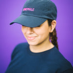Person wearing a blue cap and black t-shirt with text against a purple background