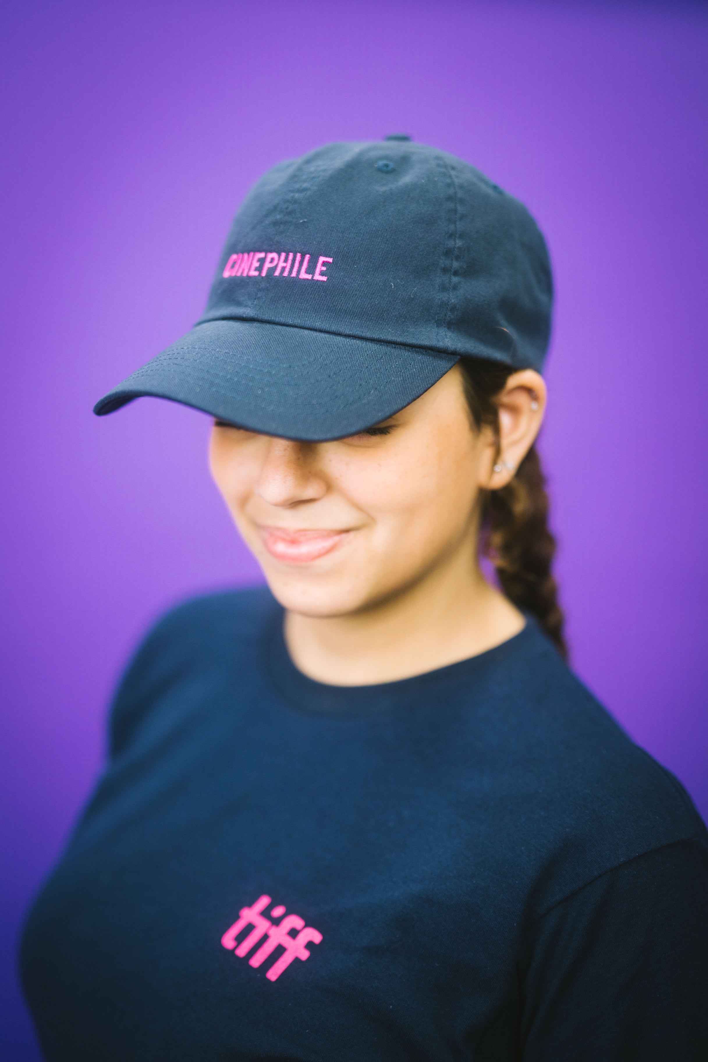Person wearing a blue cap and black t-shirt with text against a purple background