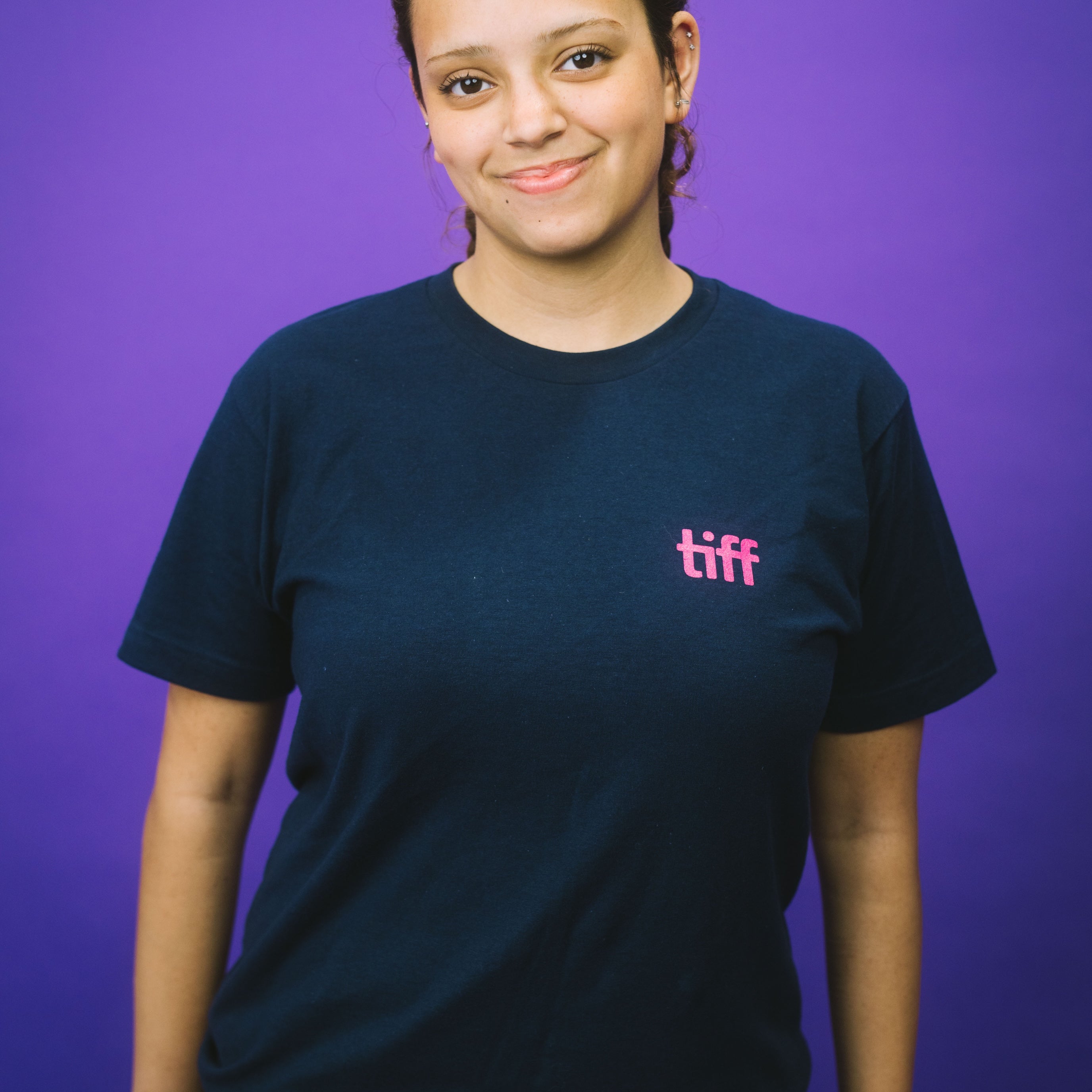 Person wearing a black t-shirt with 'tiff' logo on a purple background