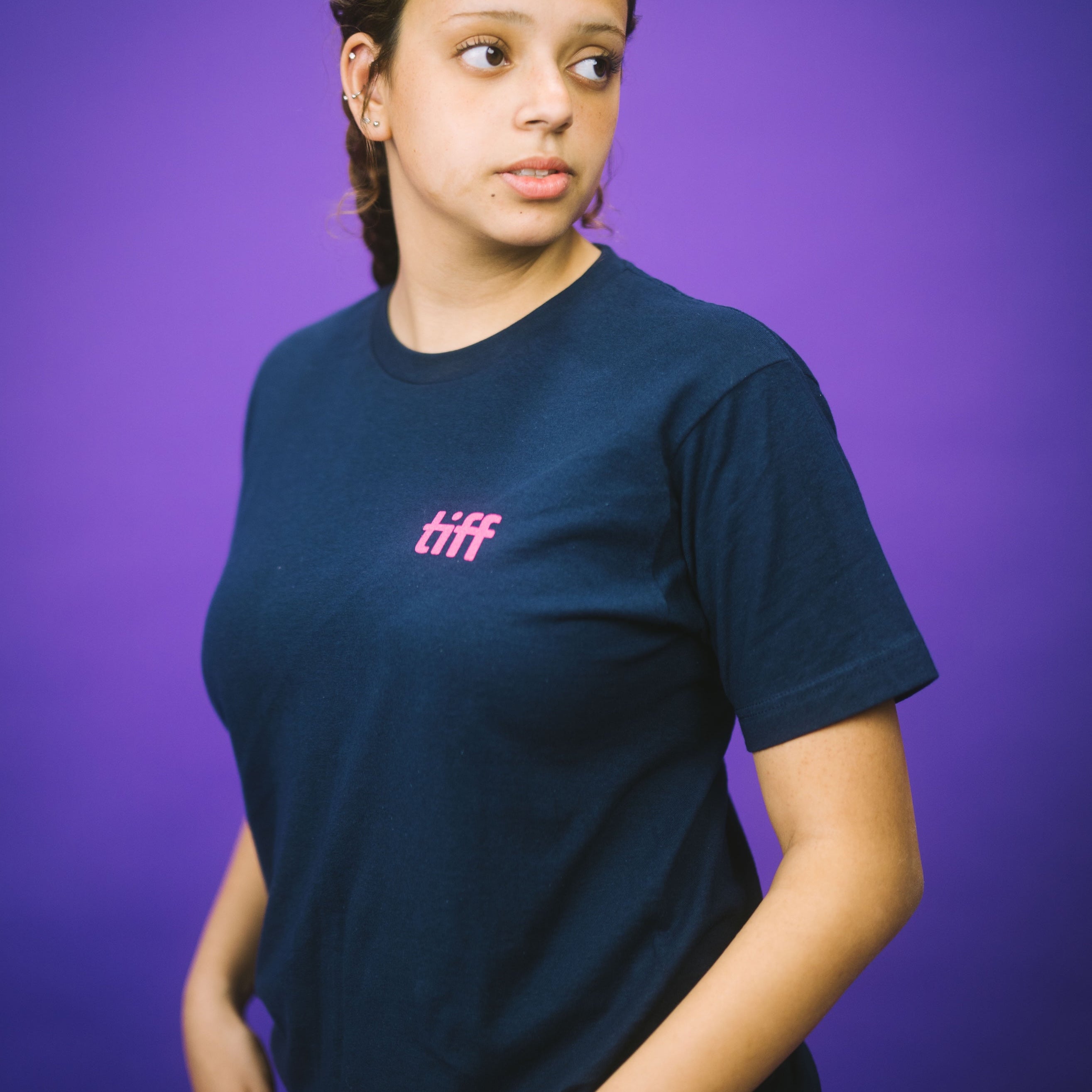 Person wearing a navy blue t-shirt with 'tiff' printed in pink on a purple background