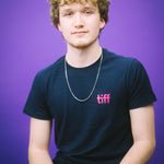 Person wearing a black t-shirt with 'tiff' logo against a purple background