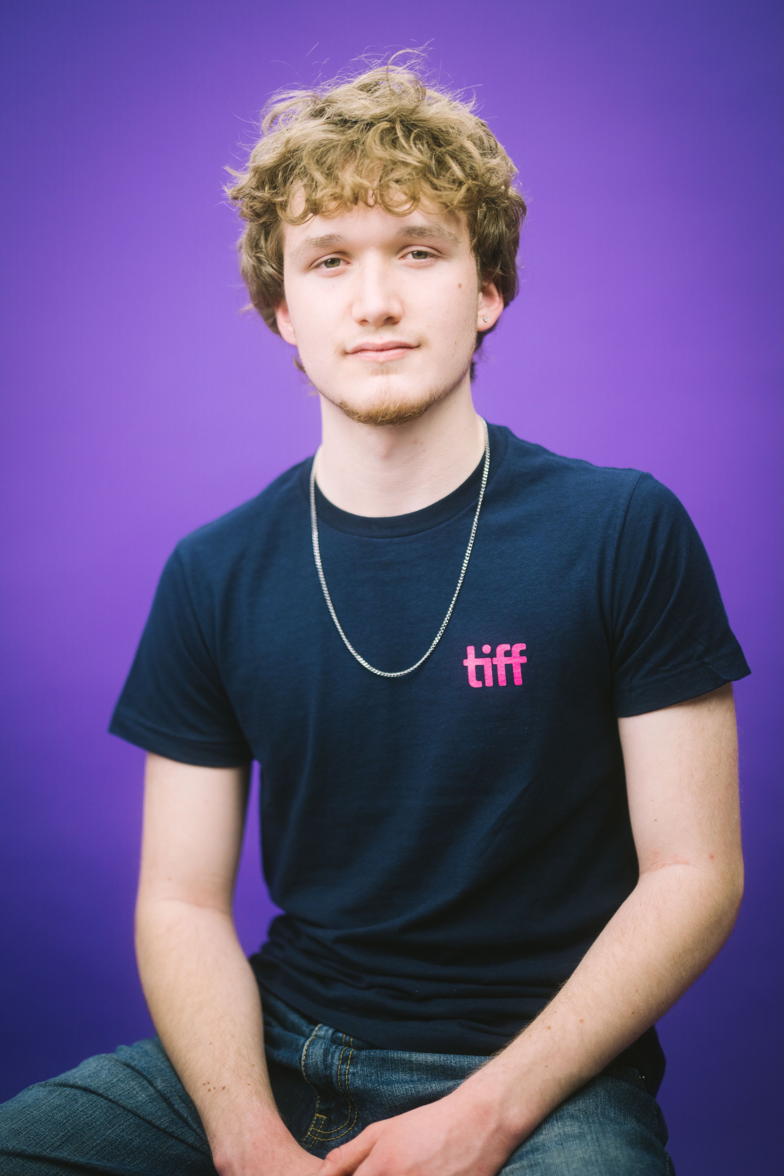 Person wearing a black t-shirt with 'tiff' logo against a purple background