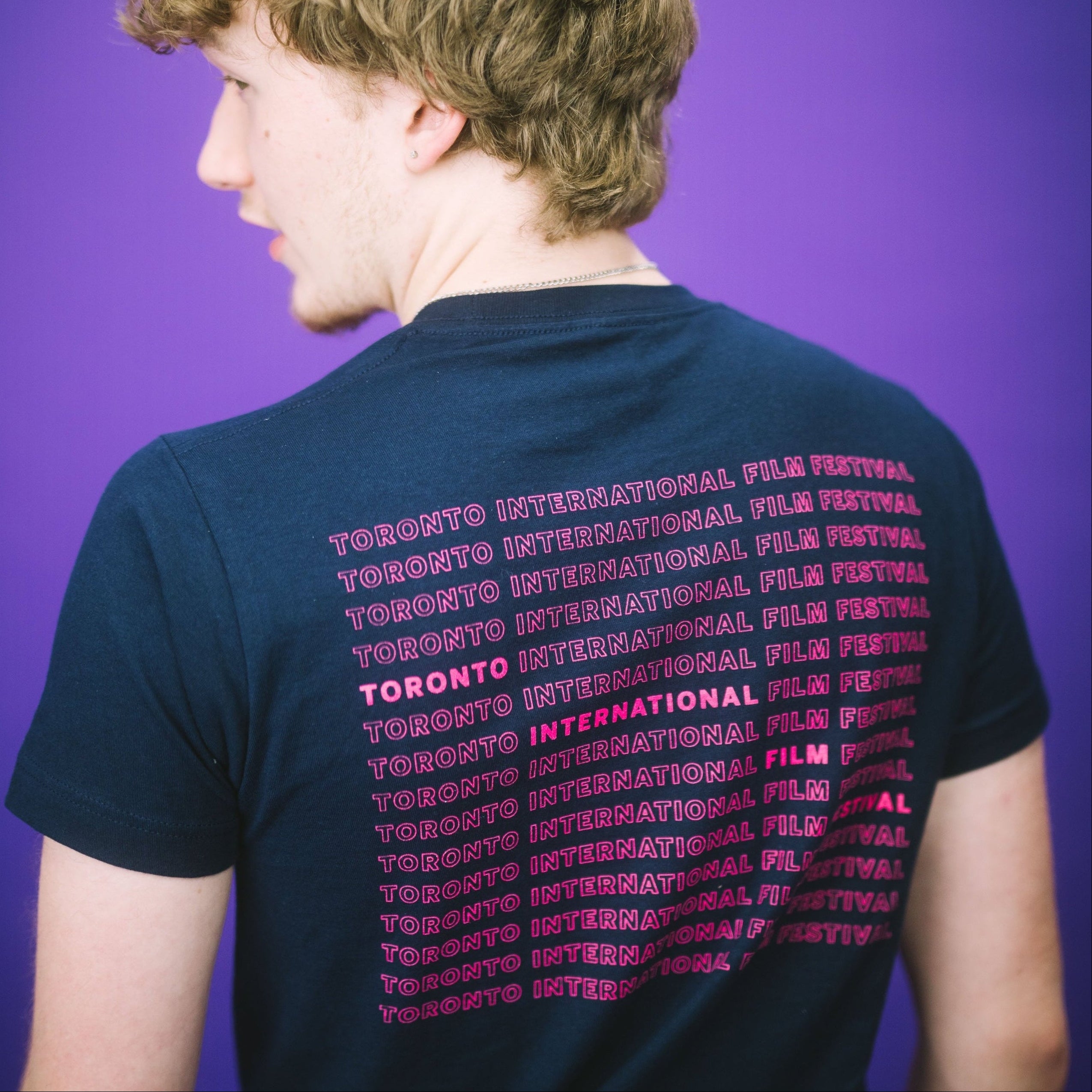 Back of person wearing T Shirt with Toronto International Film Festival written in a repeating design. 