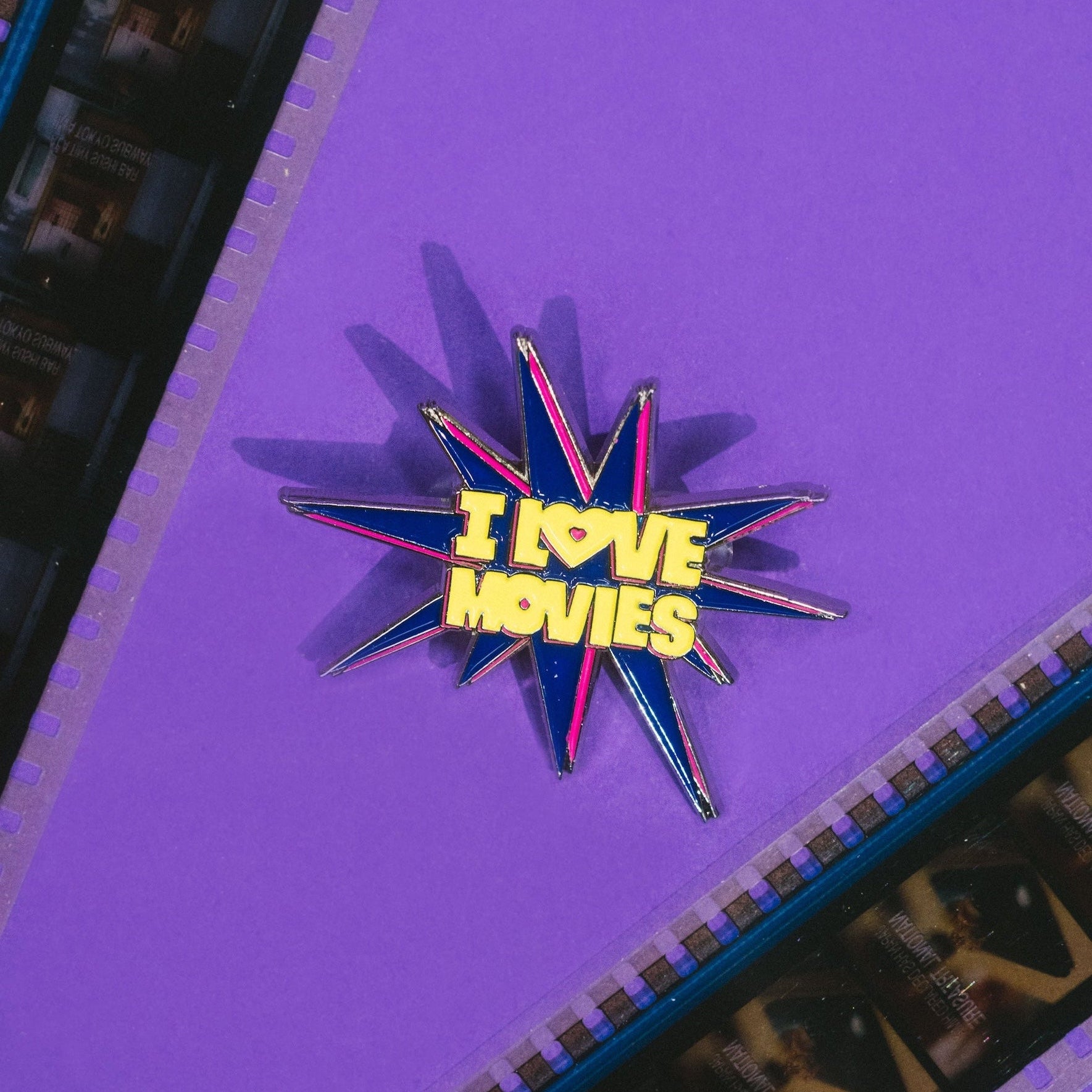 Star-shaped pin with 'I Love Movies' text on a purple background with filmstrip