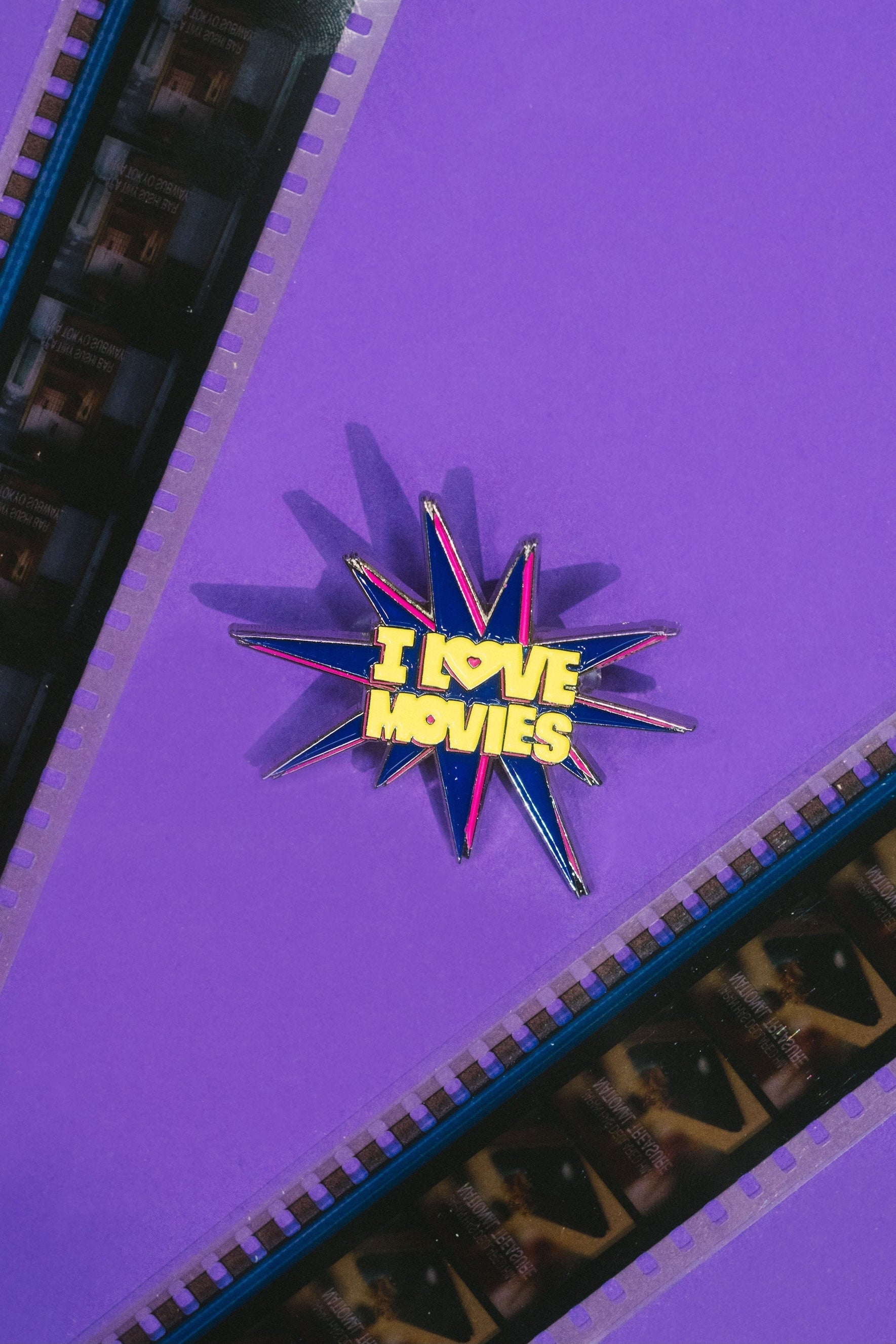 Star-shaped pin with 'I Love Movies' text on a purple background with filmstrip