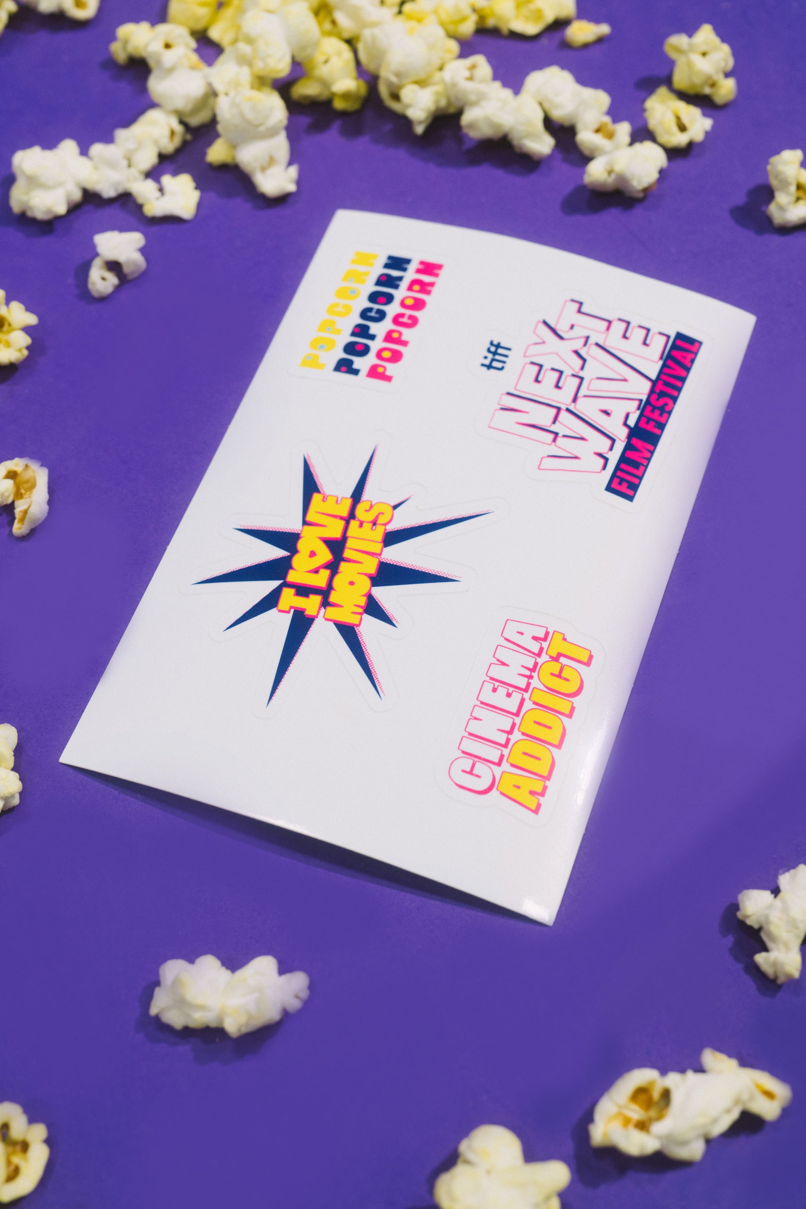 Popcorn and a card with movie festival text on a purple background