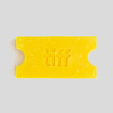 A bright yellow wax melt or soap bar shaped like a movie ticket, embossed with the word 'tiff' in the center, on a solid light gray background.