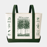 A canvas tote bag featuring dark green straps and base with a cream-colored body adorned with green botanical illustrations, literary quotes, and a central image of a garden gate.