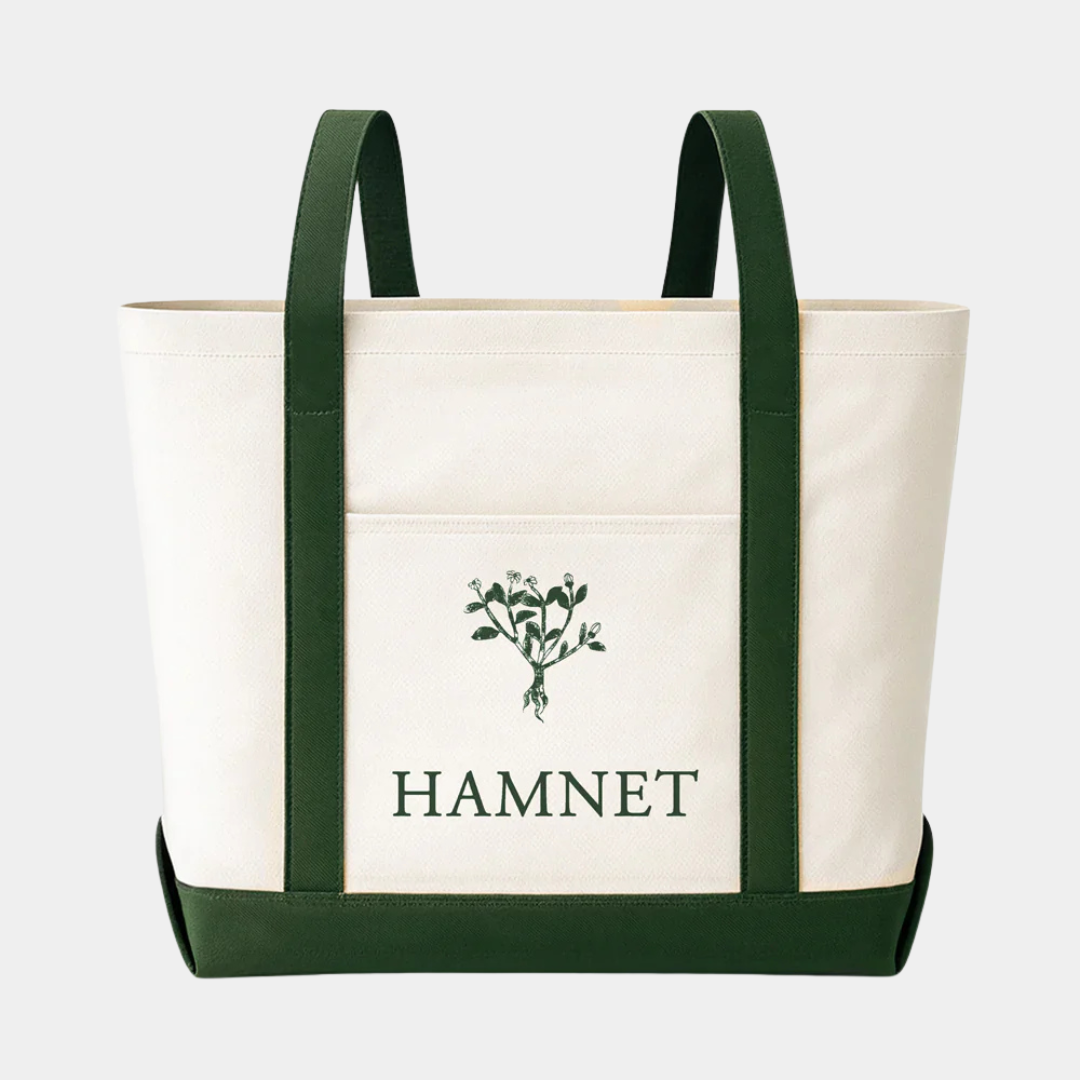 A cream-colored canvas tote bag featuring dark green vertical straps and a matching base, with a central pocket displaying a green botanical illustration above the word "HAMNET" in bold, green serif letters.