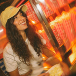 Woman in a yellow cap smiling in front of a popcorn machine