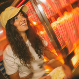 Woman in a yellow cap smiling in front of a popcorn machine