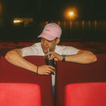 Two people sitting in red theater seats at night, drinking sodas.