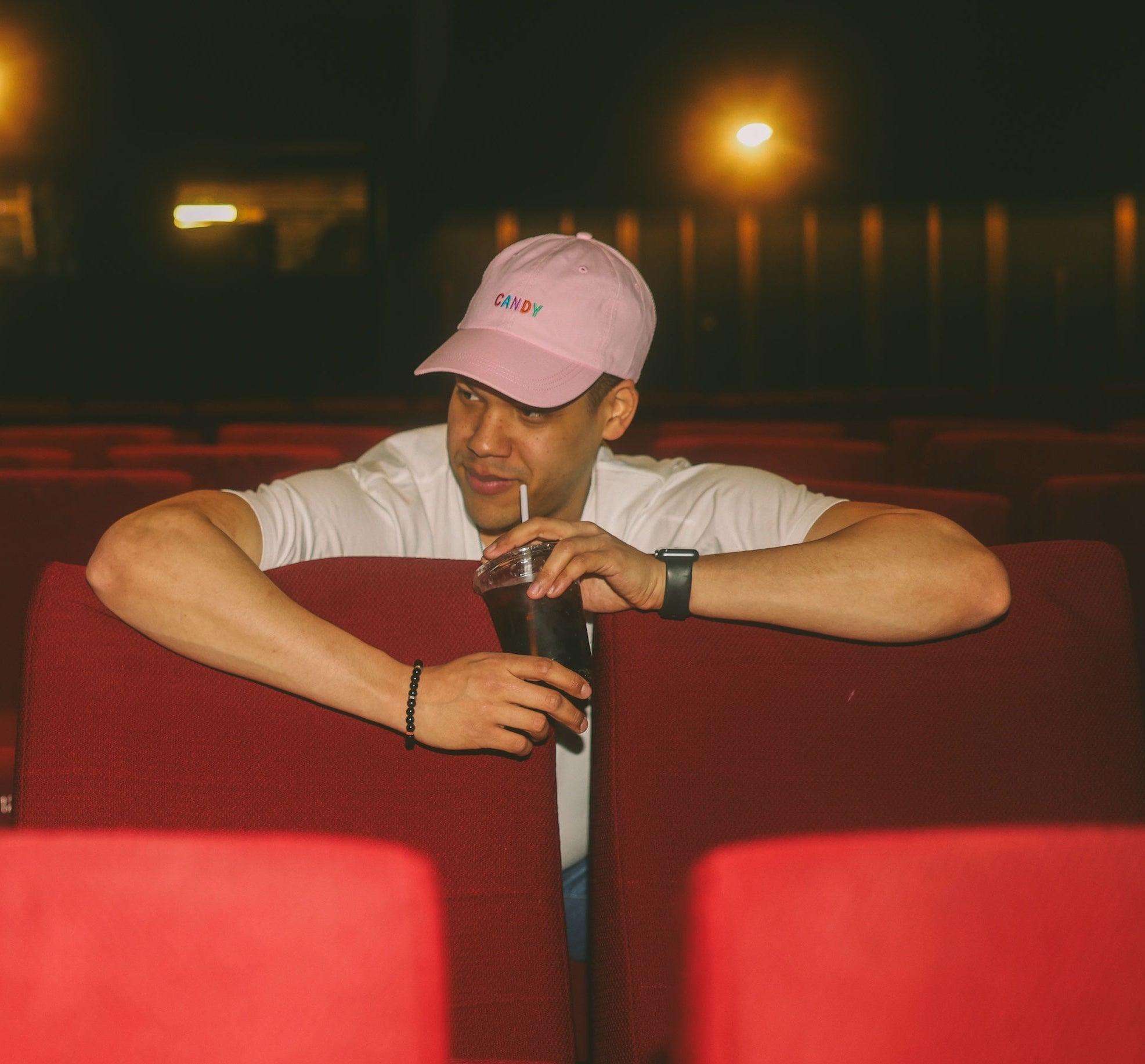Two people sitting in red theater seats at night, drinking sodas.