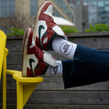 A person wearing jeans rests their feet on a yellow chair, showcasing brown Nike sneakers and white socks that feature a black circle with the words "Inside Out."