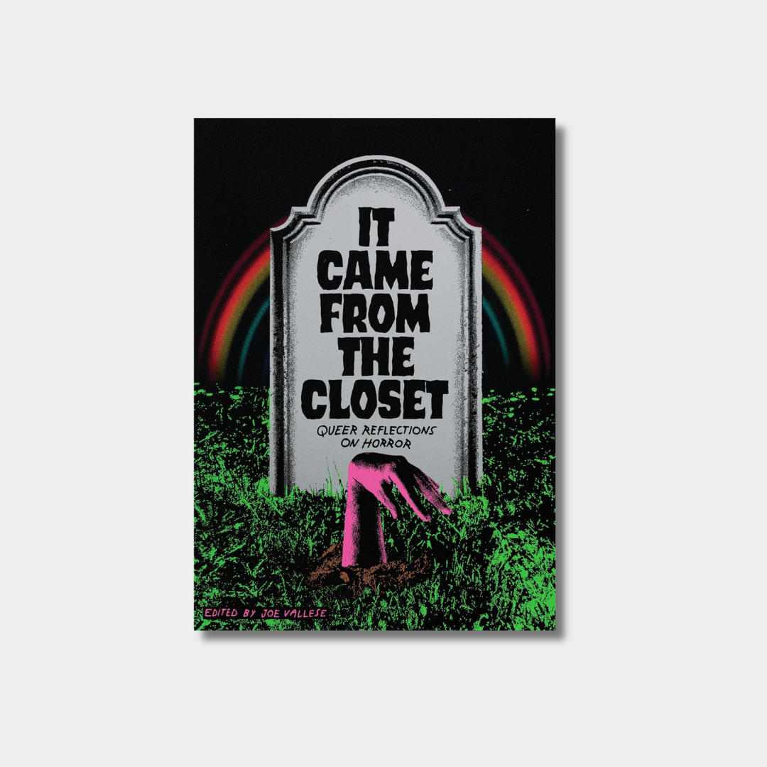 An illustrated book cover featuring a grey tombstone with the title "IT CAME FROM THE CLOSET: QUEER REFLECTIONS ON HORROR" inscribed on it, set against a dark background with a colorful rainbow arch and a pink zombie hand emerging from the green grass below.
