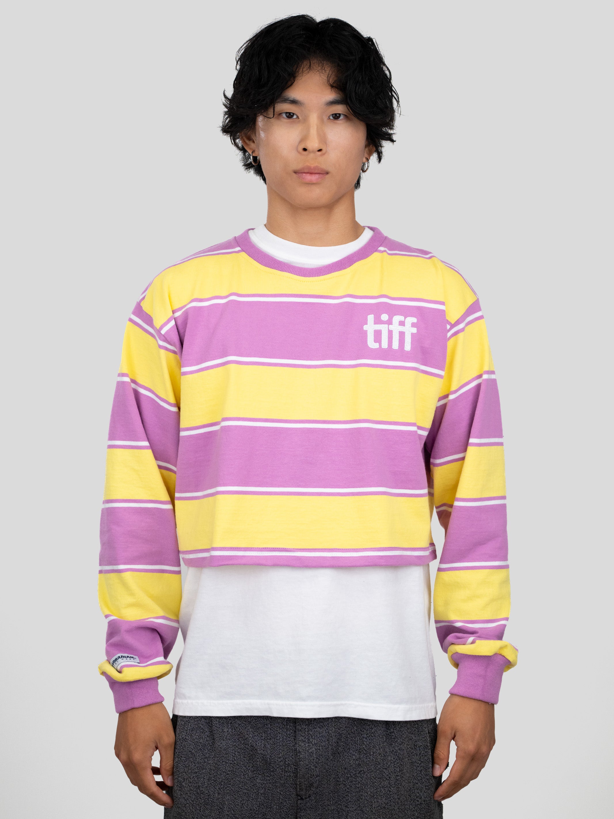 A model wears a long-sleeved cropped shirt featuring yellow, purple, and white stripes with the "TIFF" logo printed on the chest.
