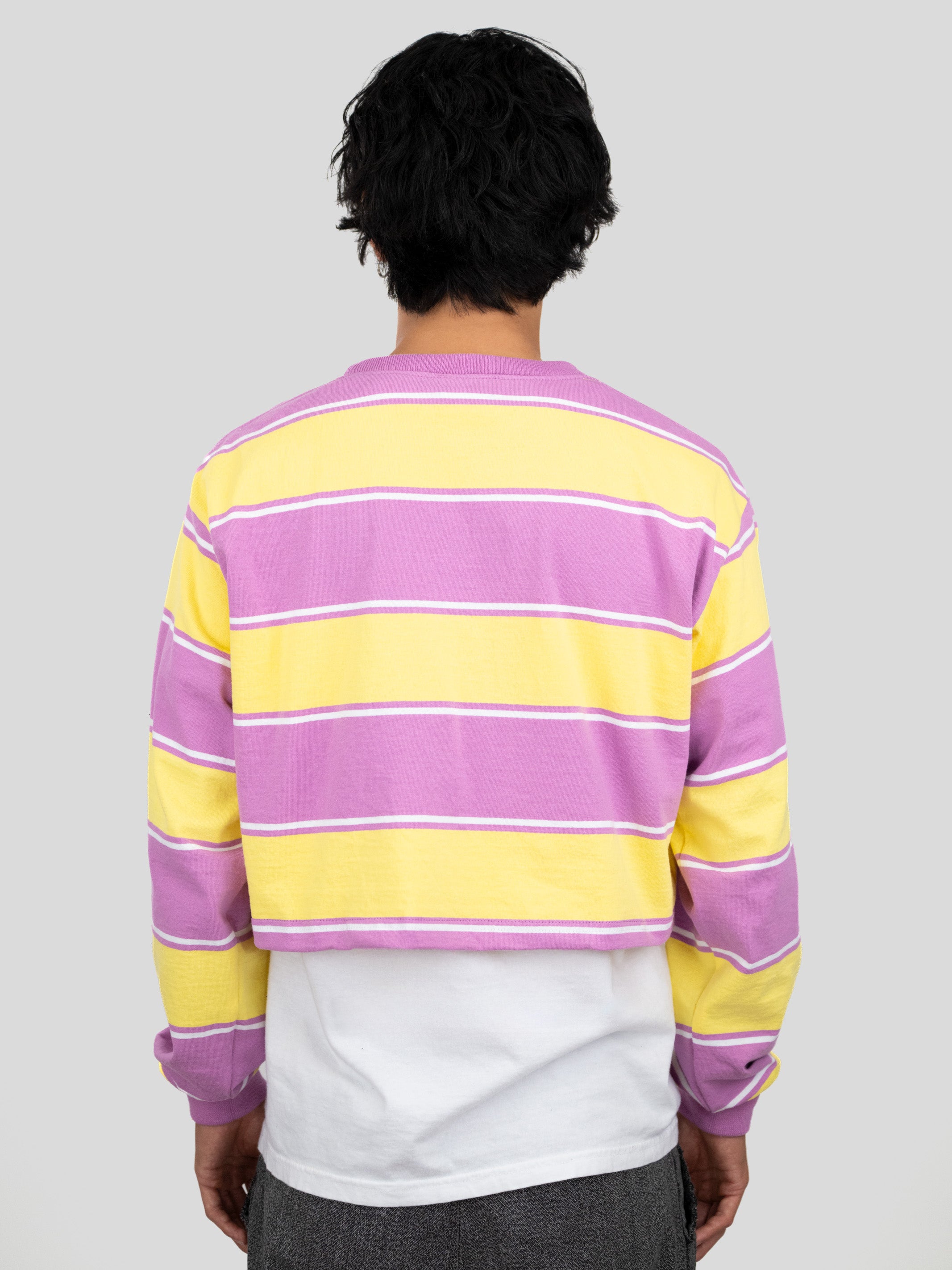 Back of model wearing a long-sleeved cropped shirt featuring yellow, purple, and white stripes.