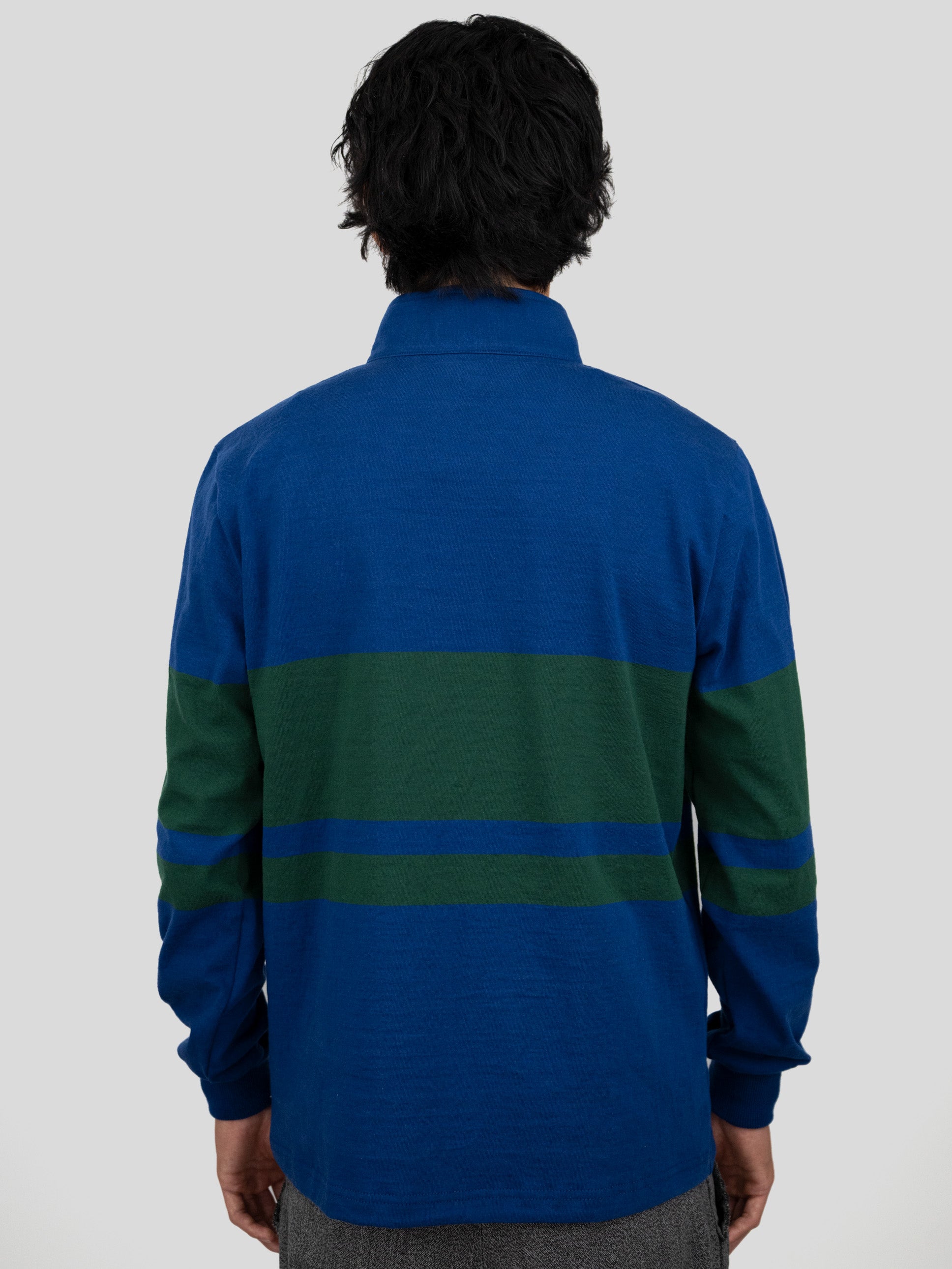 Back of model wearing a blue and dark green quarter-zip pullover.