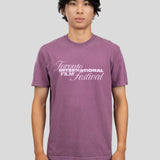 A man wearing a heathered purple t-shirt with a white graphic print that reads 'Toronto International Film Festival' on the chest, standing against a solid gray background.
