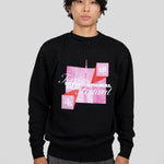 A man wearing a black crewneck sweatshirt with a pink and white graphic print for the Toronto International Film Festival, paired with gray trousers, against a solid light gray background.