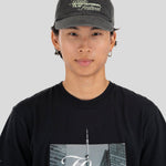 A person wearing a dark gray textured baseball cap with 'Toronto International Film Festival' embroidered on the front, paired with a black graphic t-shirt, against a solid light gray background.