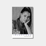 A black and white book cover titled "Julie Dash: Interviews" featuring a portrait of a woman with long braids resting her head on her hand against a simple, textured studio backdrop.