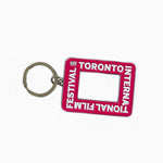 A pink rectangular enamel keychain featuring the Toronto International Film Festival logo and a cutout center resembling a camera viewfinder.