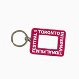 A pink rectangular enamel keychain featuring the Toronto International Film Festival logo and a cutout center resembling a camera viewfinder.
